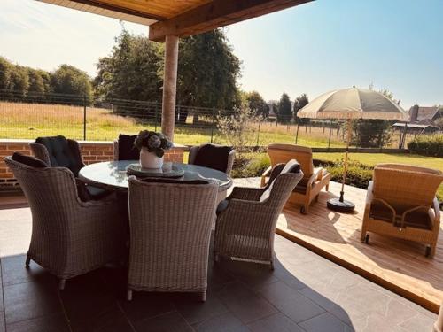 a patio with a table and chairs and an umbrella at Charmante woning in de Vlaamse Ardennen in Sint-Lievens-Houtem