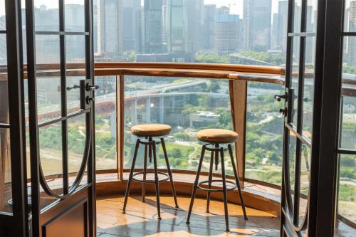 two stools on a balcony with a view of a city at Chongqing Shangshanzhu Riverside View Homestay in Chongqing