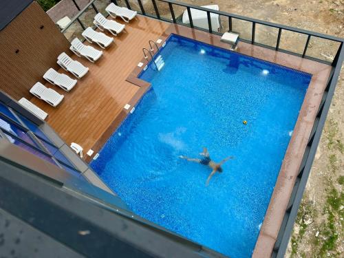 a man swimming in a swimming pool with chairs at Gonio Studio in Batumi in Kvariati