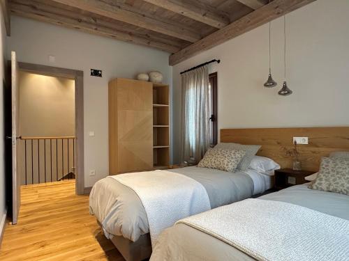 two beds in a room with wooden floors at Casa Rural Pacelia in Salgüero de Juarros