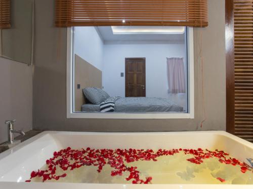 a bath tub with red flowers in it with a mirror at 88 Fine Hotel @ Suratthani Airport in Surat Thani