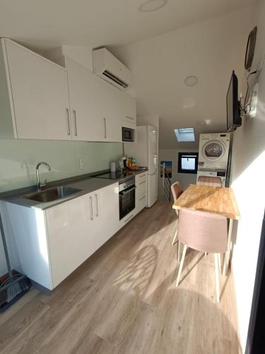 a kitchen with white cabinets and a wooden table at La Casita de Vane - Casa en el centro con parking privado a unos 250 metros in Cangas de Morrazo