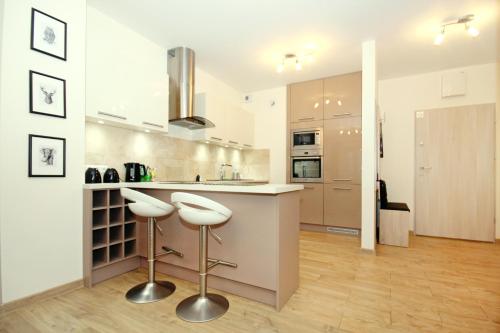 a kitchen with two stools and a counter top at Livin Apartments Santocka in Szczecin