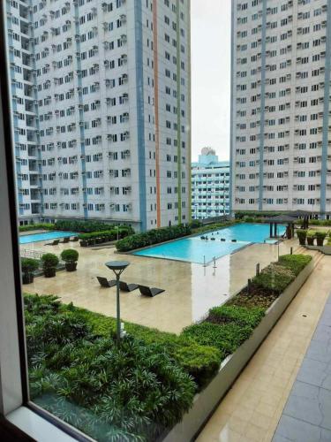 a view of a swimming pool in a city with tall buildings at Cozy Studio Unit in Quezon City with Private Pool and City Views in Manila
