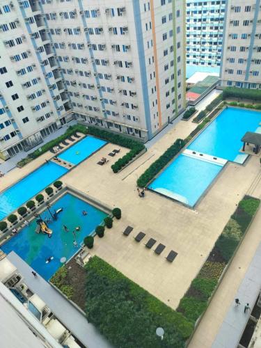 an aerial view of two pools in a city with tall buildings at Cozy Studio Unit in Quezon City with Private Pool and City Views in Manila