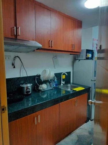 a kitchen with wooden cabinets and a black counter top at Modern Condo in Quezon City with Private Pool and City Views in Manila