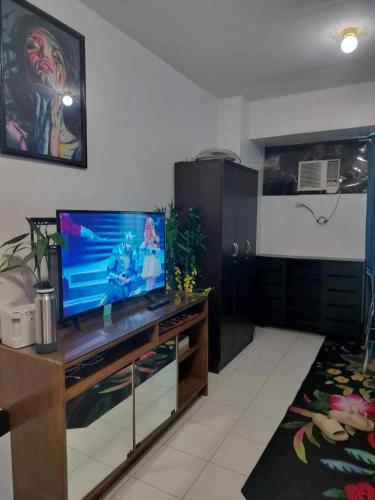 a living room with a flat screen tv on a entertainment center at Modern Condo in Quezon City with Private Pool and City Views in Manila