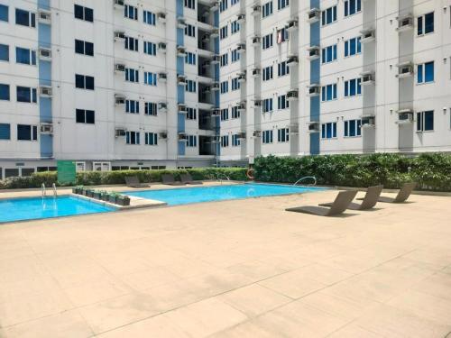a swimming pool in front of a large apartment building at Modern Condo in Quezon City with Private Pool and City Views in Manila