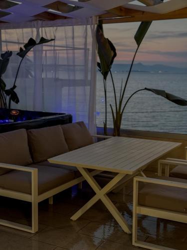 a table and a couch in a room with the ocean at Valtes Luxurious Apartment III in Mpoukaris