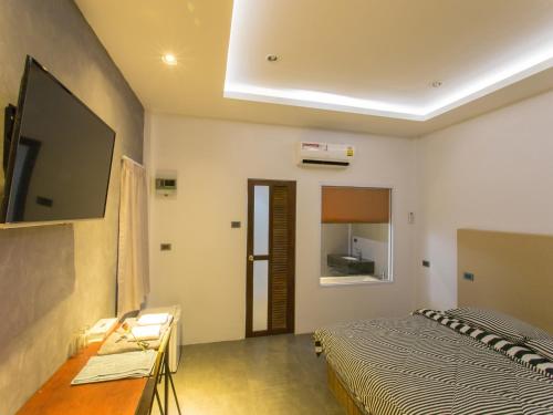 88 Fine Hotel @ Suratthani Airport في سوراثاني: غرفة نوم مع سرير وتلفزيون على الحائط
