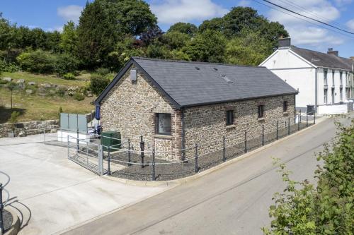 an old stone building with a fence around it at Cysgod Y Ffordd - a gorgeous new barn conversion sleeping 4 guests with disabled facilities in Carmarthen