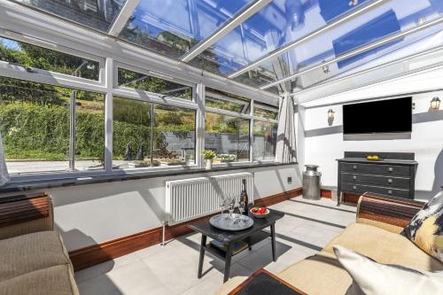 a living room with windows and a flat screen tv at Cysgod Y Ffordd - a gorgeous new barn conversion sleeping 4 guests with disabled facilities in Carmarthen