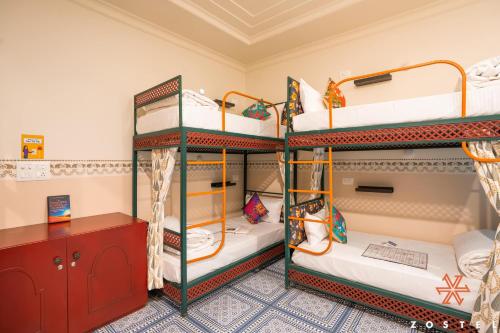 a room with three bunk beds and a desk at Zostel Agra in Agra