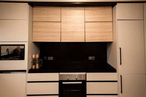a kitchen with white cabinets and a stove at 2-Bedroom Getaway- Comfort and Style in Trofwi