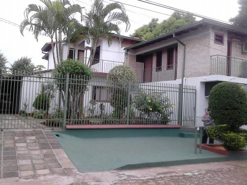 a pool in front of a house with a fence at Nueva Alborada Lodging House in Fernando de la Mora