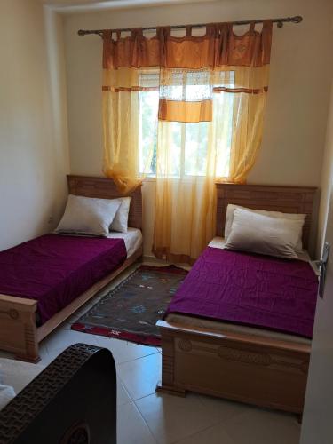 two beds in a room with a window at Meknès Escale in Meknès