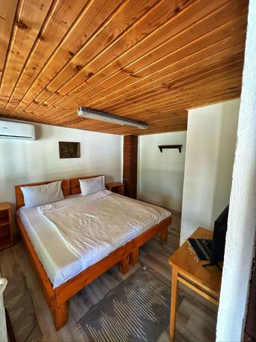 a bed in a room with a wooden ceiling at Ograda Bunicului Seaca in Gura Văii