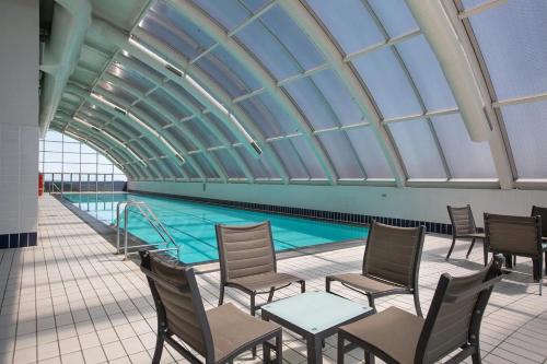 a swimming pool with chairs and a glass ceiling at Harbour Home 2BR Apt - Family Friendly Gem in Sydney