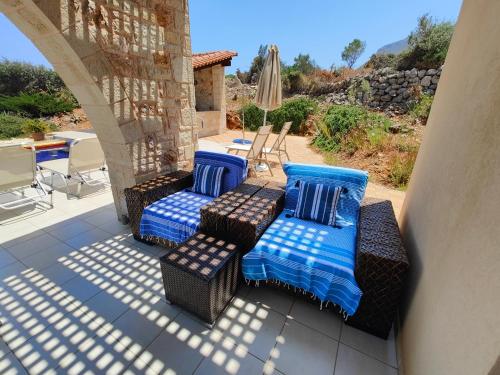 a patio with two chairs and an umbrella at Bellavista Plaka Sea View Villa in Kambiá
