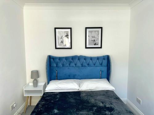 a blue bed in a white bedroom with two pictures on the wall at Elohim Double Room in London