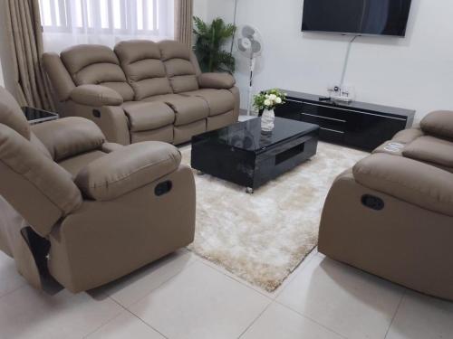a living room with two couches and a tv at Sofitel 3 bedrooms own compound milimani in Kisumu