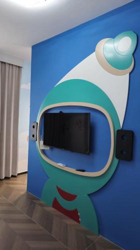 Habitación con pared azul y TV de pantalla plana. en Hermanos Apartment 110, en Shëngjin