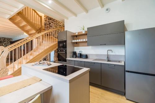 a kitchen with stainless steel appliances and a staircase at Gîte de charme à la campagne à 15 km de la mer in Saint-Clet