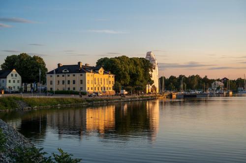 a large yellow building next to a river at Hotell Blå Blom in Gustavsberg