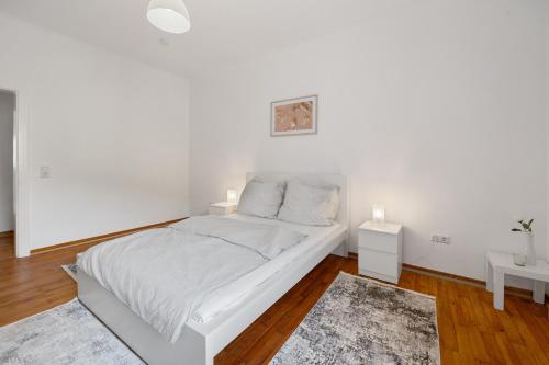 a white bedroom with a bed and two night stands at Ferienwohnung Merzig in Merzig