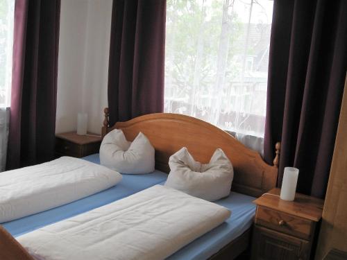 2 Betten mit weißen Kissen neben einem Fenster in der Unterkunft Hotel-Restaurant Cafe Caro in Carolinensiel