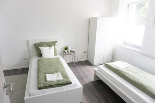 Un dormitorio blanco con dos camas y una ventana. en Ferienwohnung Zur Wieskapelle W2 - ideal für Monteure, en Straubing