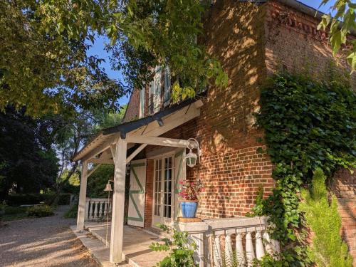 a brick building with an awning and a porch at Maison familiale - La Rabouillère in Englancourt