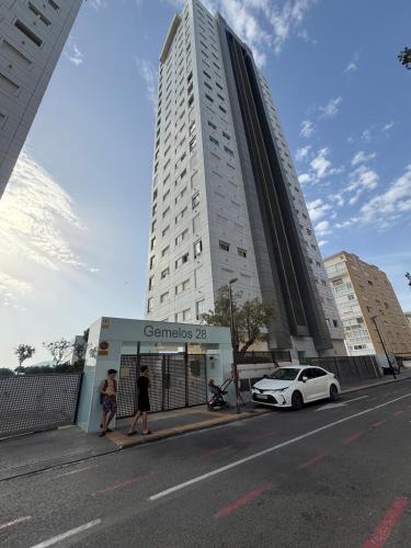a white car parked in front of a tall building at Excellent apartment in front of the sea! in Benidorm