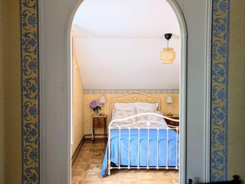 a bedroom with a blue and white bed and an archway at Maison familiale - La Rabouillère in Englancourt