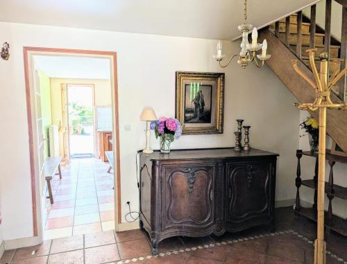 a room with a wooden cabinet with flowers on it at Maison familiale - La Rabouillère in Englancourt