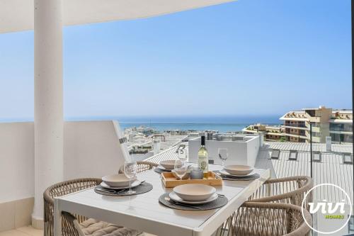 a table with a bottle of wine on a balcony with the ocean at Mimosa in Fuengirola