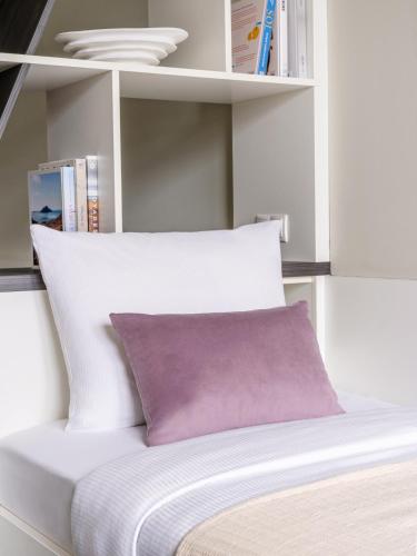 a bed with a purple pillow in a book shelf at Numa Munich Viktoria in Munich