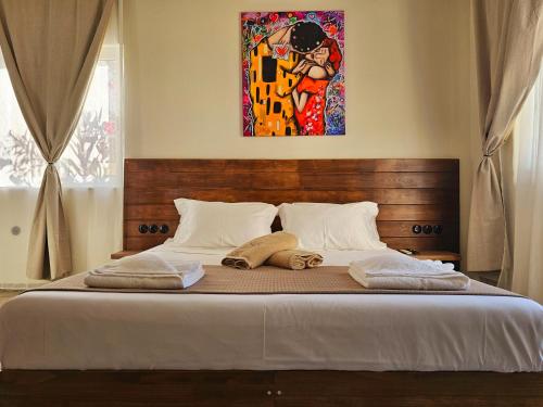 a bed with two pillows and a painting on the wall at BROWN ON GREEN a stone house with amazing view in Drapaniás