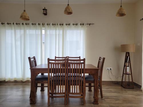 a dining room with a wooden table and chairs at The Ark Haven Ooty in Kolakambe