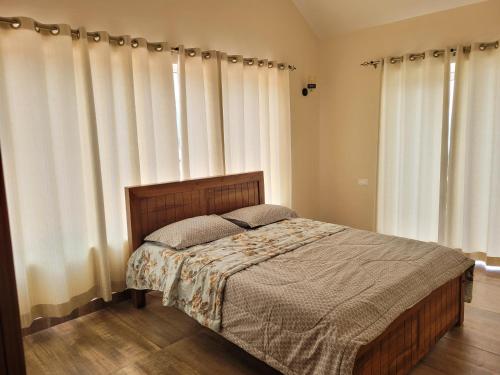 a bedroom with a large bed with white curtains at The Ark Haven Ooty in Kolakambe