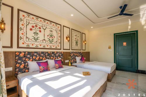 two beds in a room with paintings on the wall at Zostel Agra in Agra