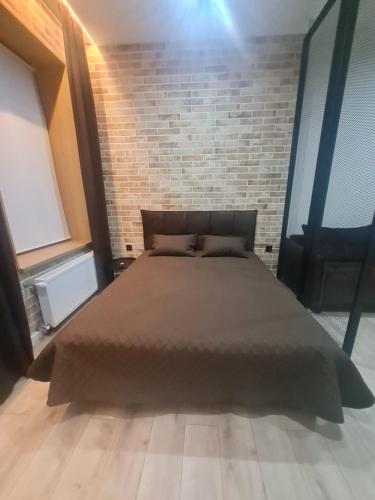 a bed in a room with a brick wall at Апартаменти в центрі по вул Л Українки,46 in Luts'k