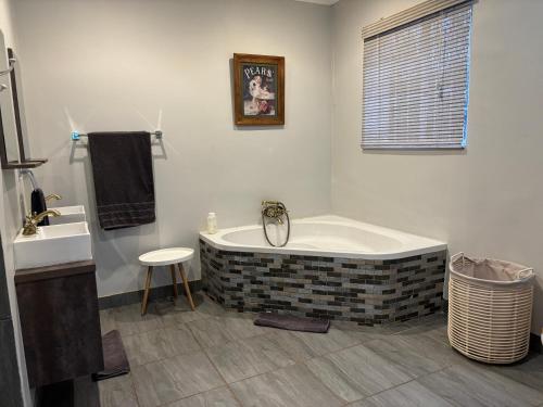 a bathroom with a bath tub and a sink at DullVino Wellington House in Dullstroom