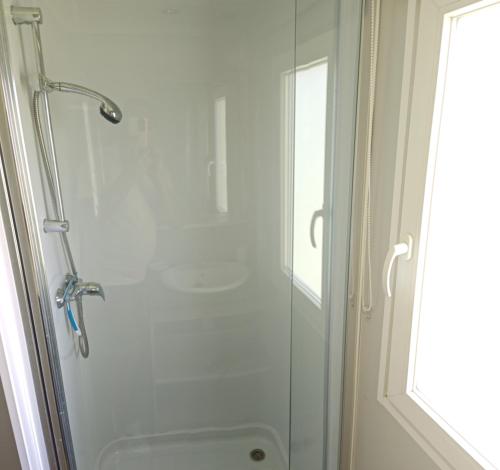 une douche avec une porte vitrée dans une salle de bain dans l'établissement Mobilhome 6 personnes, à Cheval-Blanc