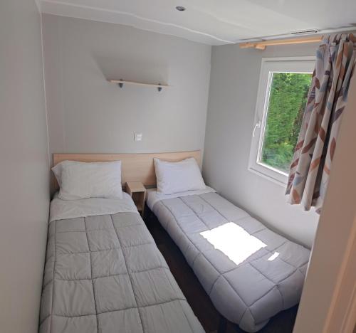 deux lits dans une petite pièce avec une fenêtre dans l'établissement Mobilhome 6 personnes, à Cheval-Blanc