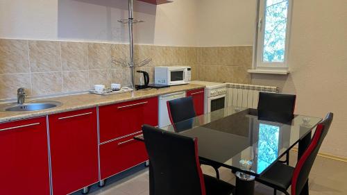 a kitchen with red cabinets and a table with chairs at JEPPESEN RESIDENCE in Almaty