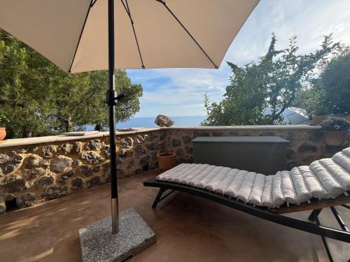 a bench with an umbrella on a patio at Pituresque stonehouse with endless view in Prosílion