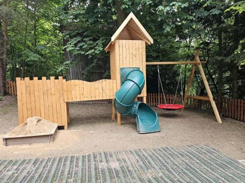 a playground with a blue slide and a swing at Chalupa Mezi stromy 