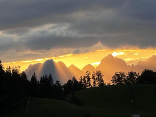 a sunset in the mountains with clouds and trees at Obinghof in Fieberbrunn