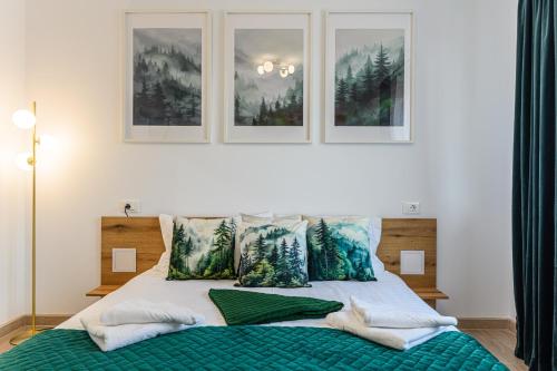 a bedroom with a bed with three pictures on the wall at Mountain Views Urban Plaza in Braşov